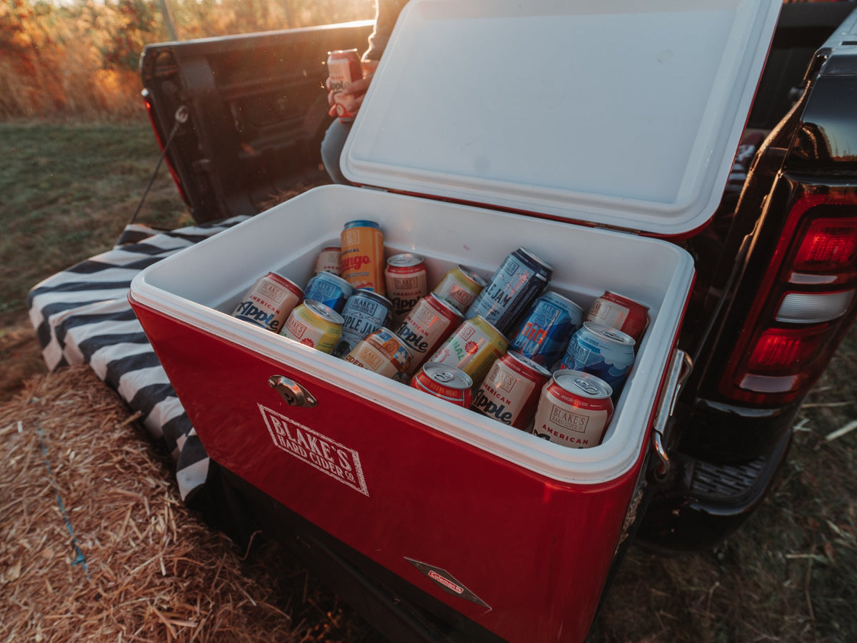 A cooler of Blake's Hard Cider cans in the back of a truck at golden hour